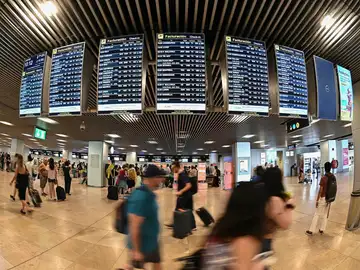 Varios pasajeros pasan por las pantallas de información en el aeropuerto Adolfo Suárez Madrid-Barajas.