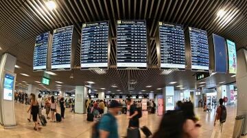 Varios pasajeros pasan por las pantallas de información en el aeropuerto Adolfo Suárez Madrid-Barajas.