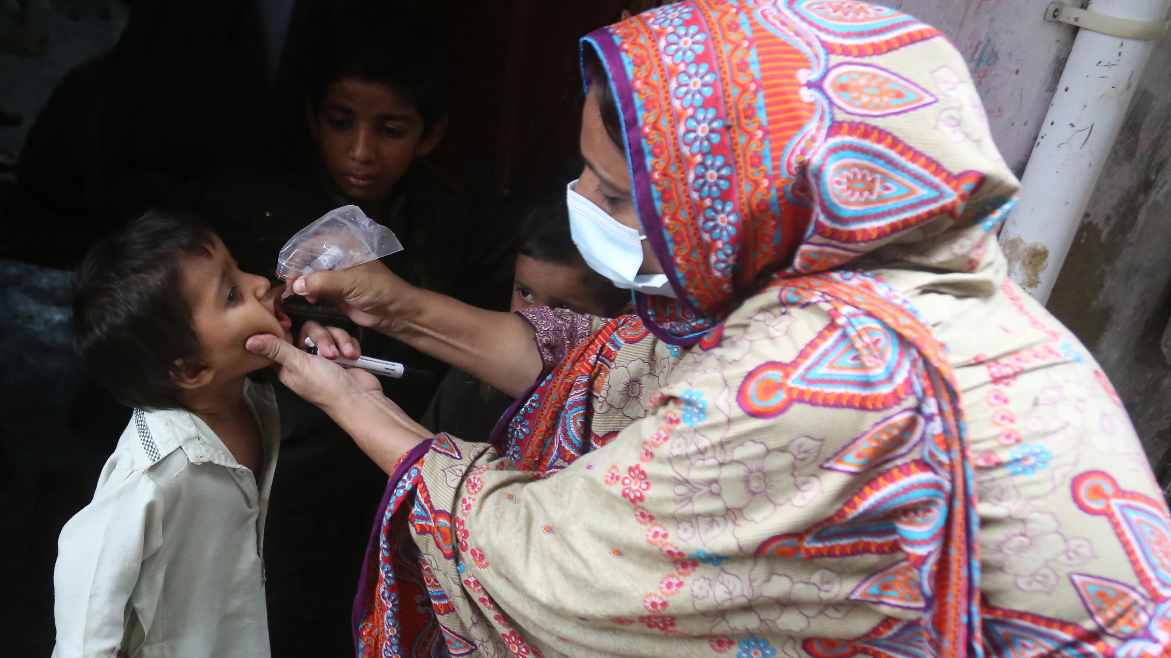 Una mujer suministra la vacuna contra la poliomelitis a un niño en Pakistán