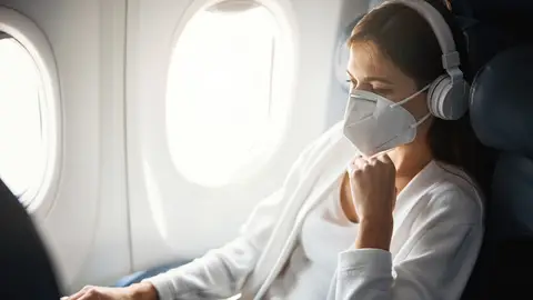 Chica con mascarilla en el avión Chica con mascarilla en el avión
