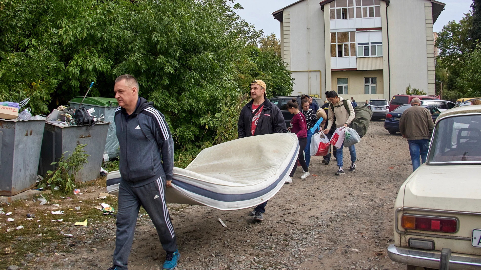Personas trasladan sus pertenencias desde un edificio residencial dañado este lunes tras los bombardeos en Járkov