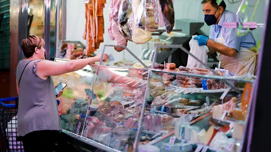 Una mujer compra en un puesto de charcutería de un mercado de Madrid, en julio Una mujer compra en un puesto de charcutería de un mercado de Madrid, en julio