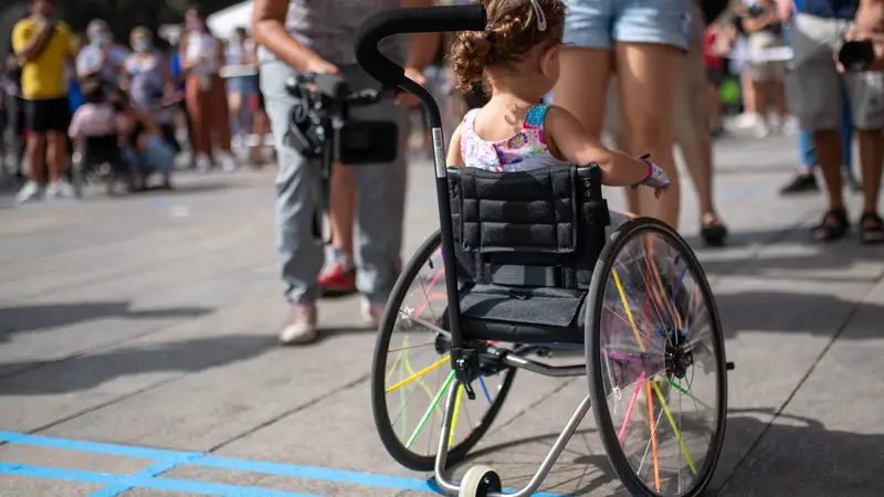 Una niña con movilidad reducida participa en una carrera adaptada.