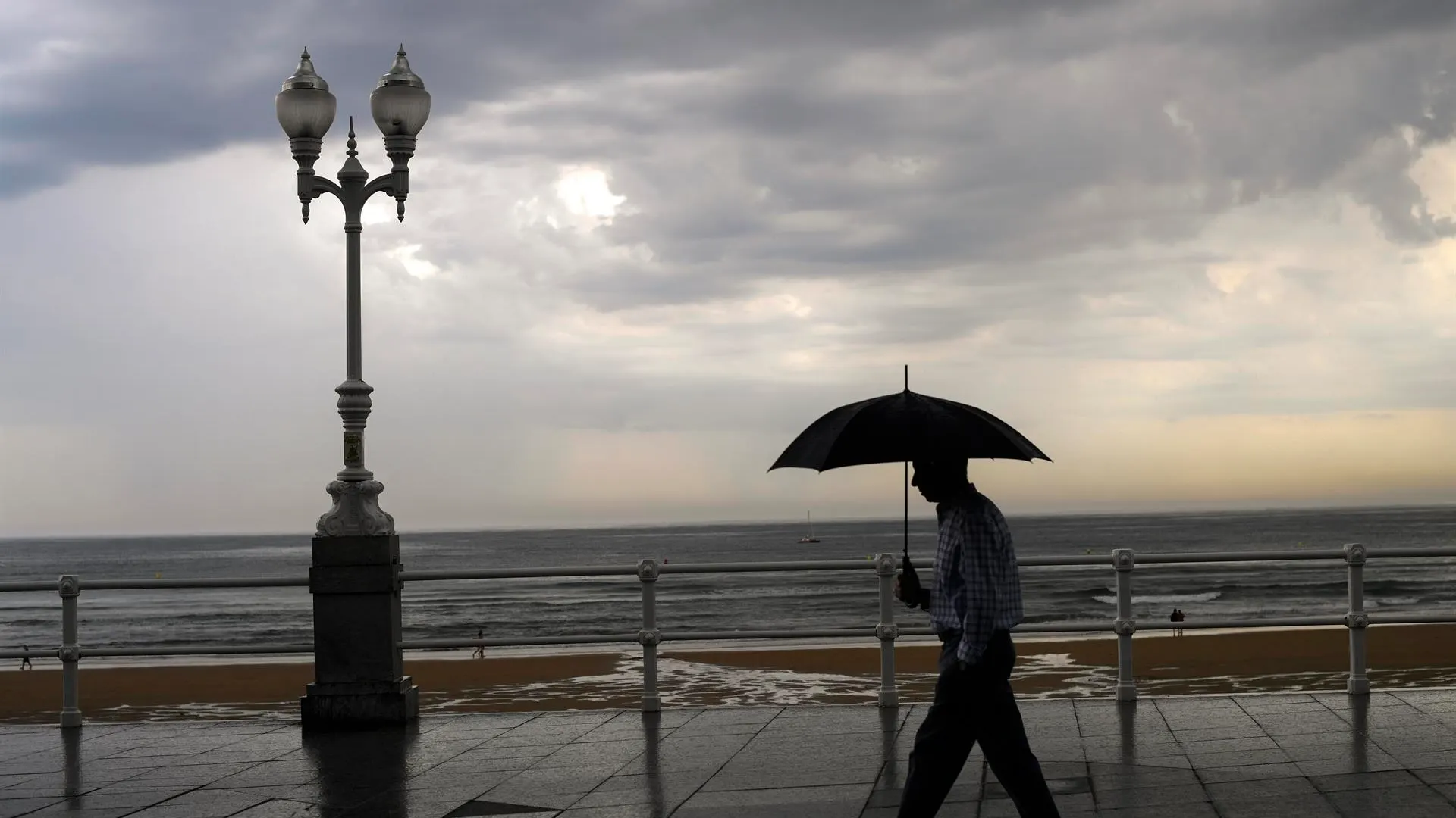 Un hombre se protege con el paraguas de la lluvia.