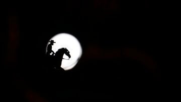 La figura de una veleta de un jinete delante de la silueta de la luna