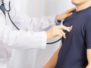 Médico auscultando a un paciente con un estetoscopio Médico auscultando a un paciente con un estetoscopio