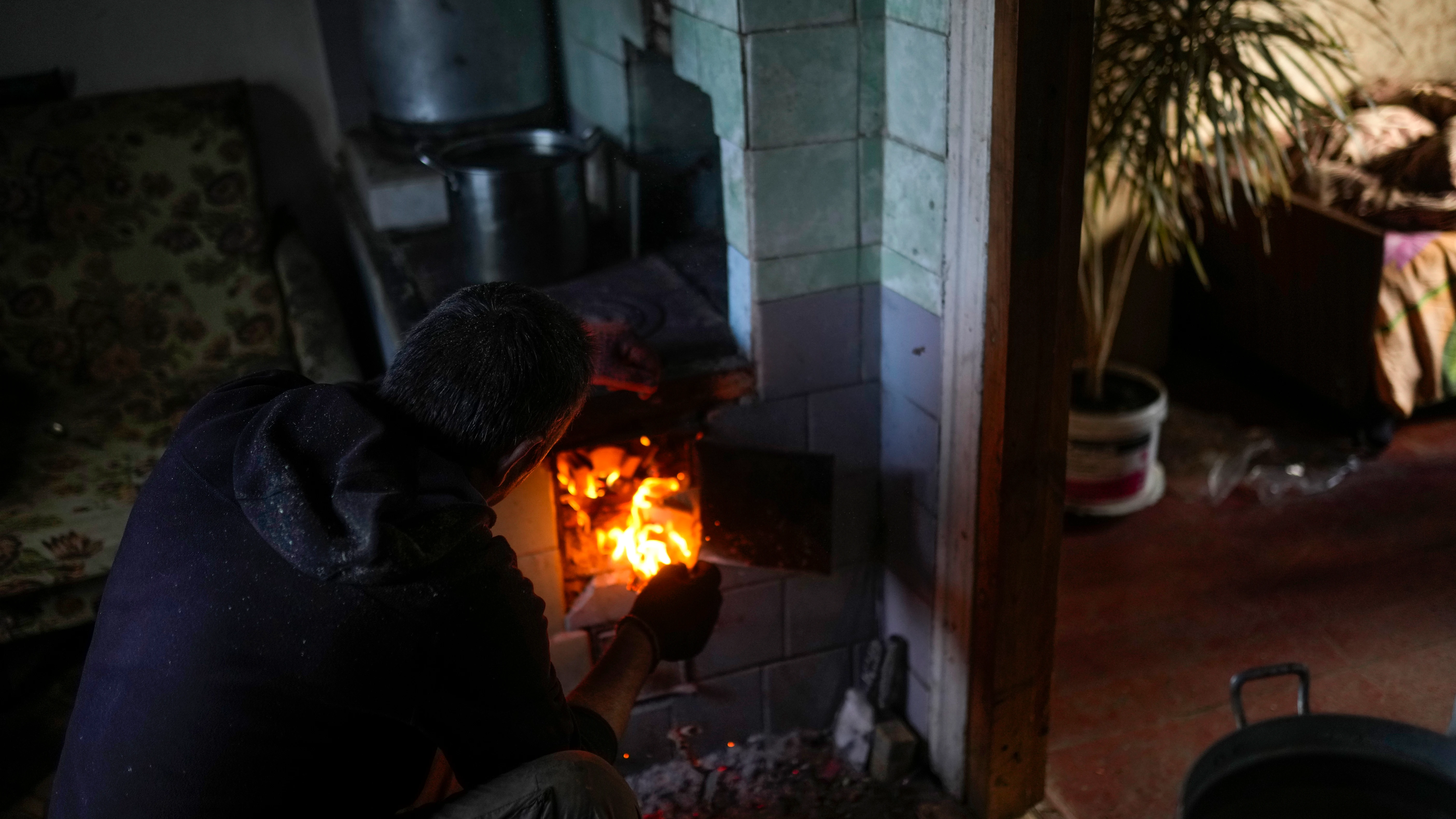 Viktor Palyanitsa enciende leña en una estufa en su casa en Kurylivka, Ucrania, el domingo 16 de octubre de 2022. 