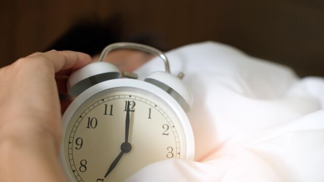 Una persona durmiendo junto a un despertador