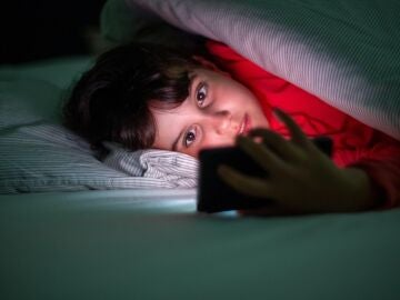 Niño con el móvil en la cama