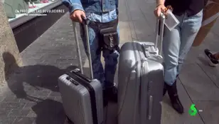 Dos jóvenes con maleta de ropa usada