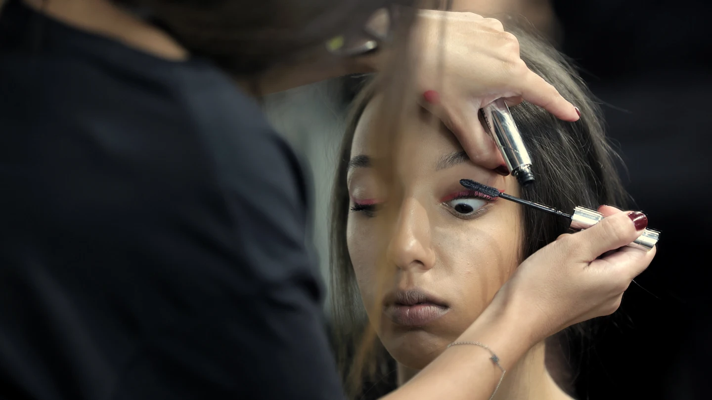 Una maquilladora maquilla a una modelo en el backstage de un desfile. Una maquilladora maquilla a una modelo en el backstage de un desfile.