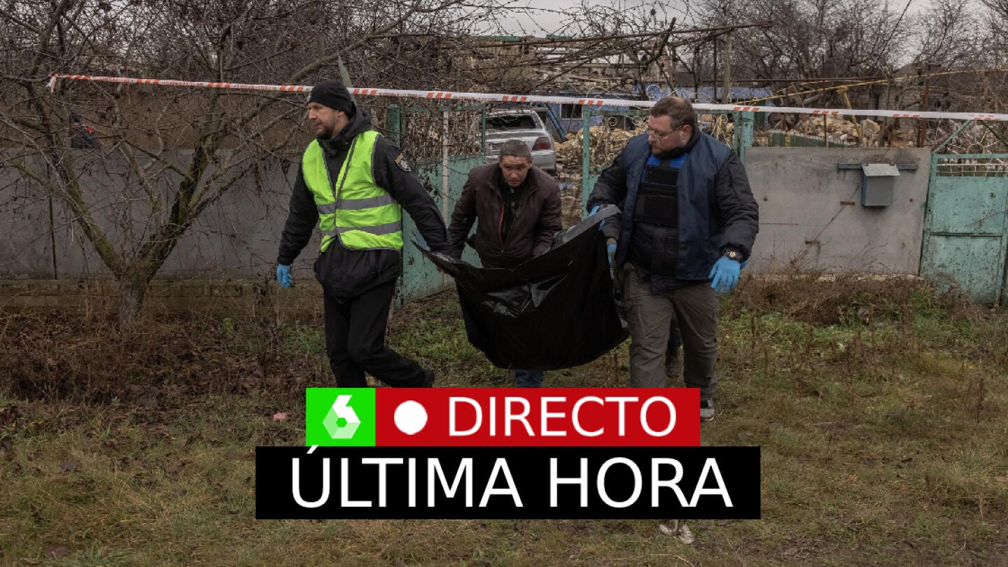 Guerra Ucrania Rusia, en directo: Residentes, polic&iacute;as, expertos forenses y fiscales de cr&iacute;menes de guerra llevan una bolsa con los restos de un civil exhumado de una fosa com&uacute;n en la aldea de Pravdyne.