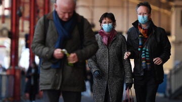 Viajeros con mascarillas en una estación de tren de Londres, Gran Bretaña.