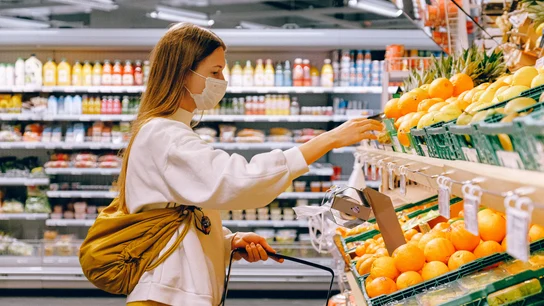 Una mujer mira los precios en el estante de un supermercado supermercado
