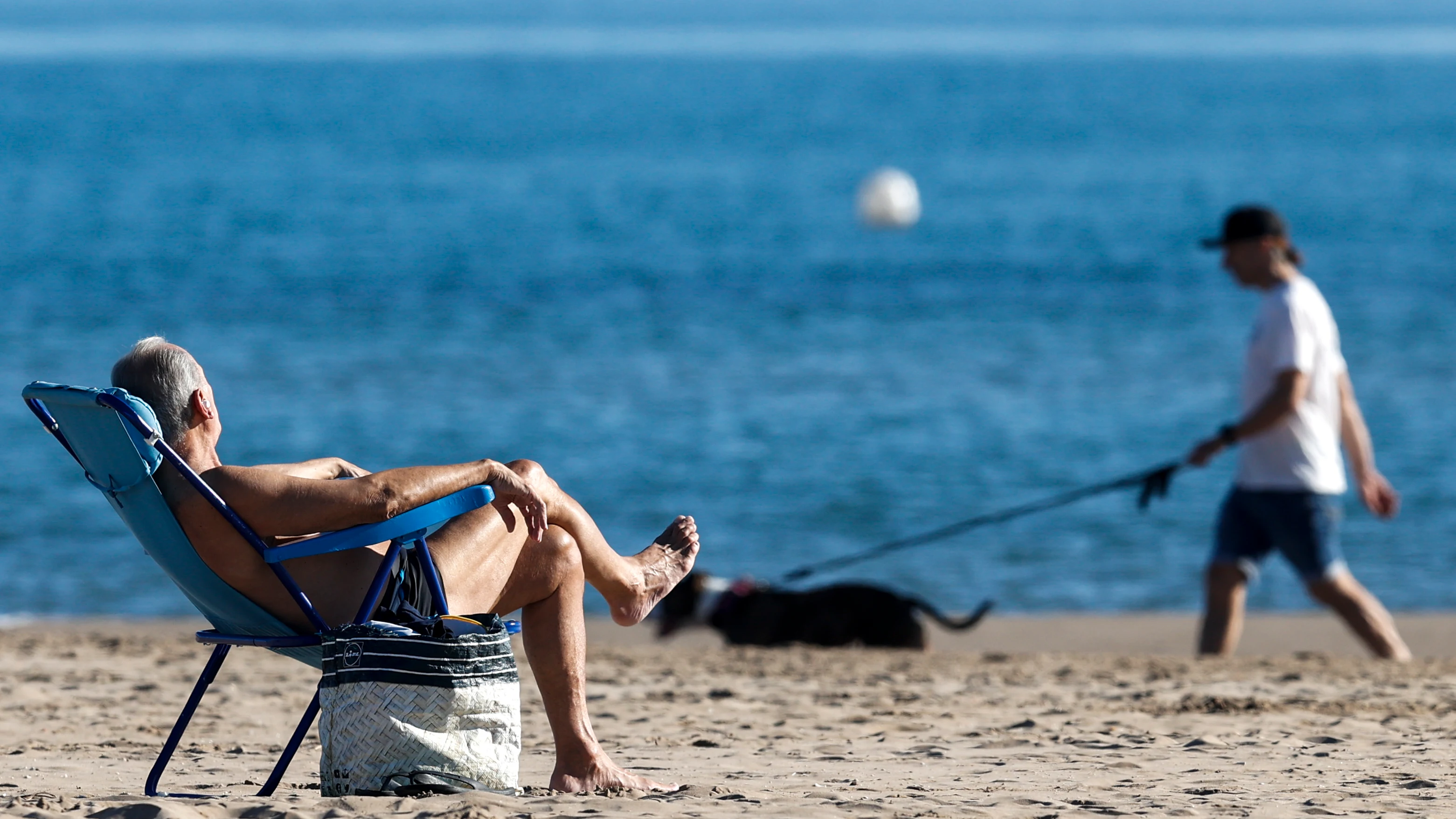 Un hombre toma el sol en la playa de la Malvarrosa.