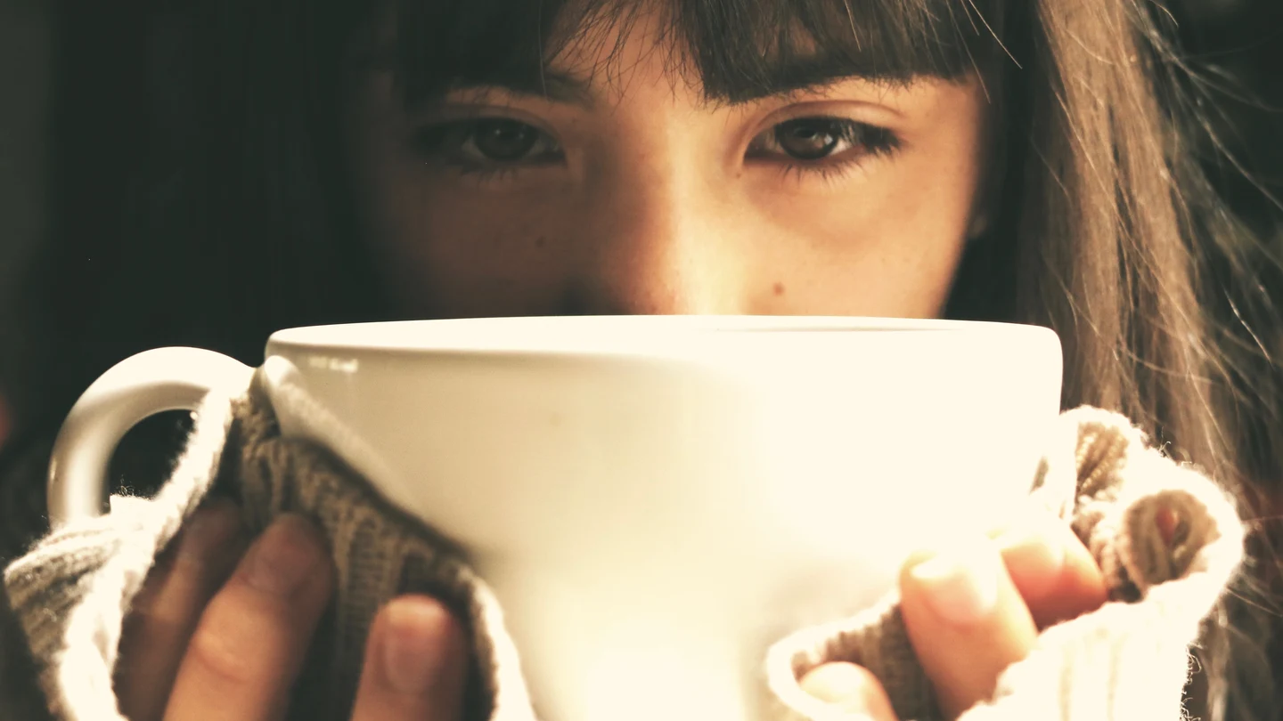 Una chica triste bebiendo de una taza. una chica triste bebiendo de una taza.
