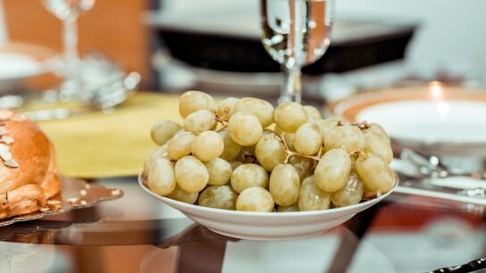 Una copa de champ&aacute;n detr&aacute;s de un plato con uvas, preparadas para Nochevieja