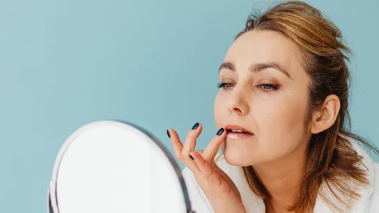 Mujer echándose crema en los labios Mujer echándose crema en los labios