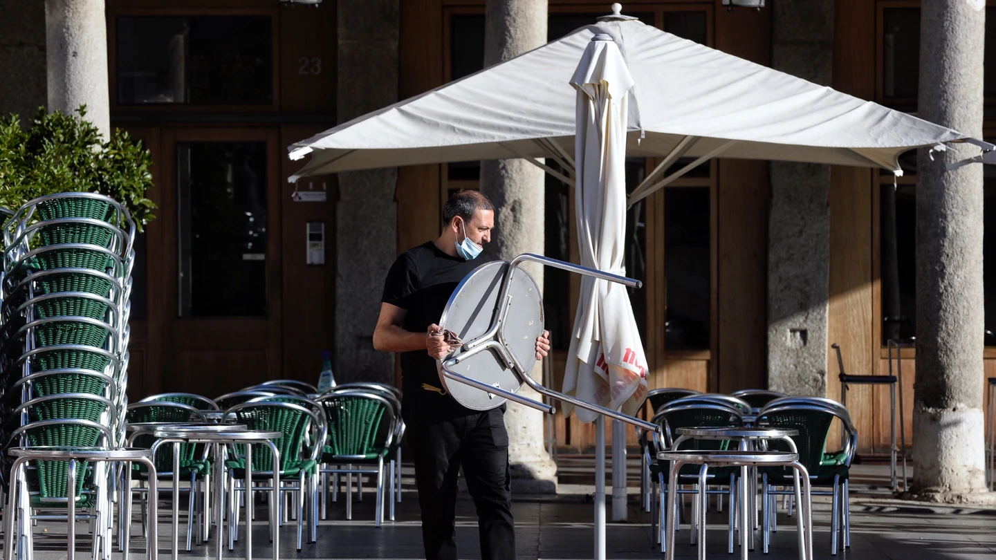 Imagen de archivo de un camarero colocando mesas en la terraza de un bar. Imagen de archivo de un camarero colocando mesas en la terraza de un bar.