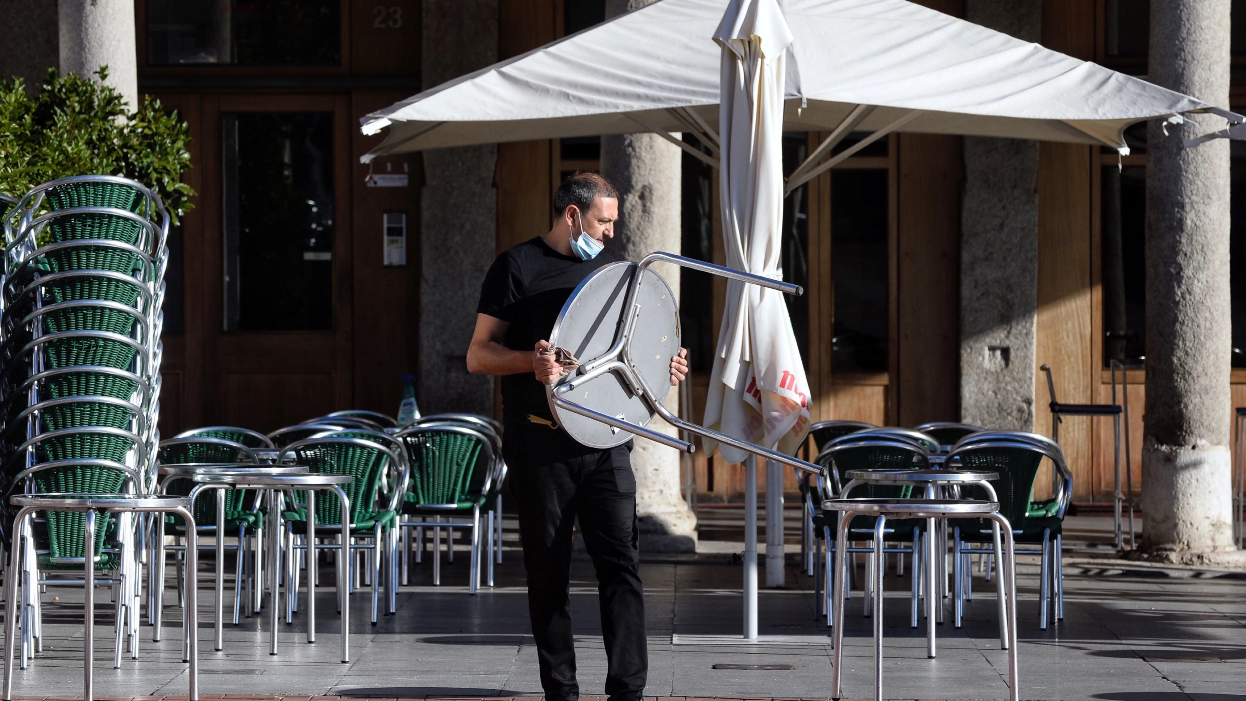 Imagen de archivo de un camarero colocando mesas en la terraza de un bar.