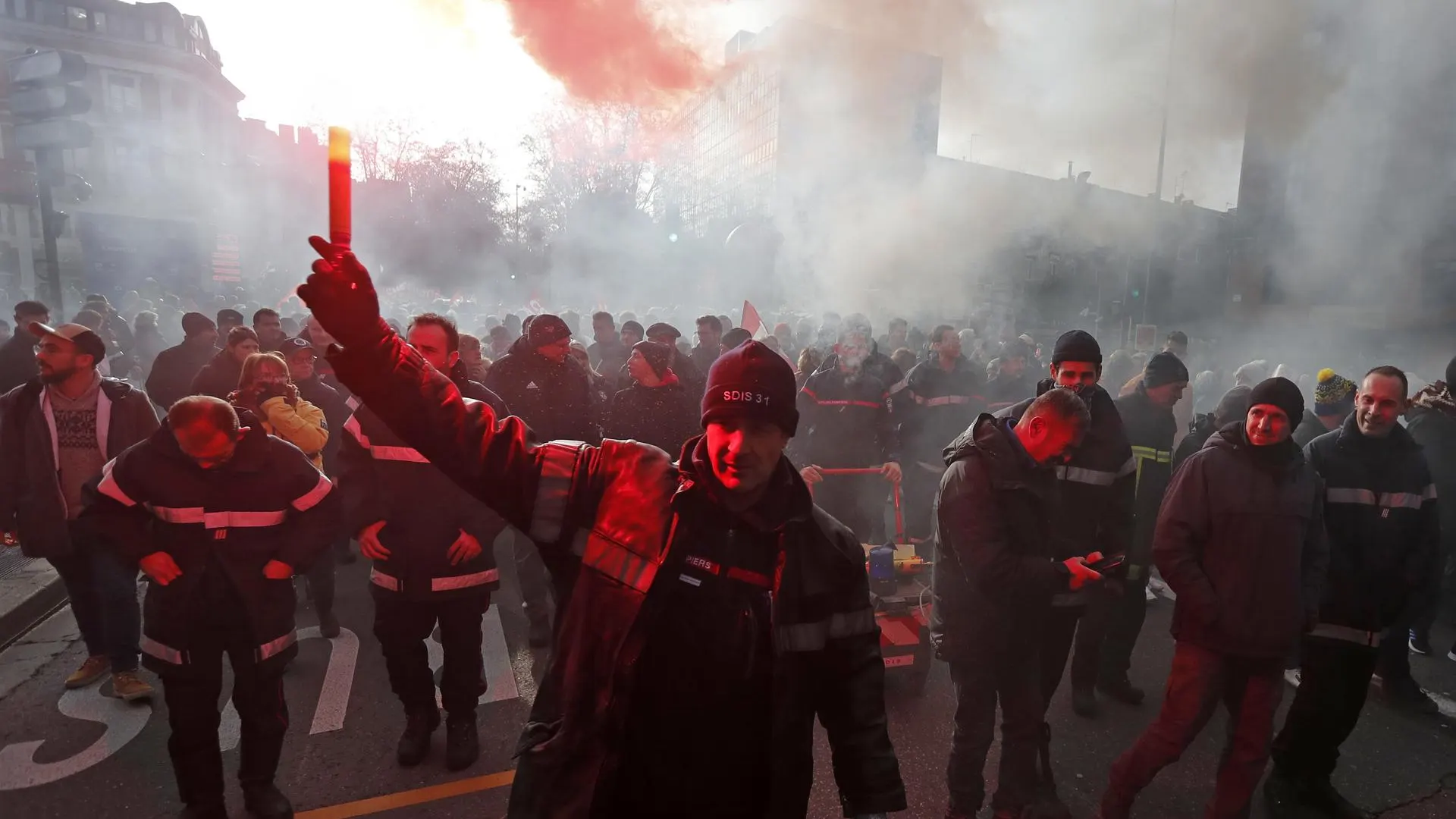 Un bombero enciende una bengala roja durante una protesta en Toulouse, en Francia.