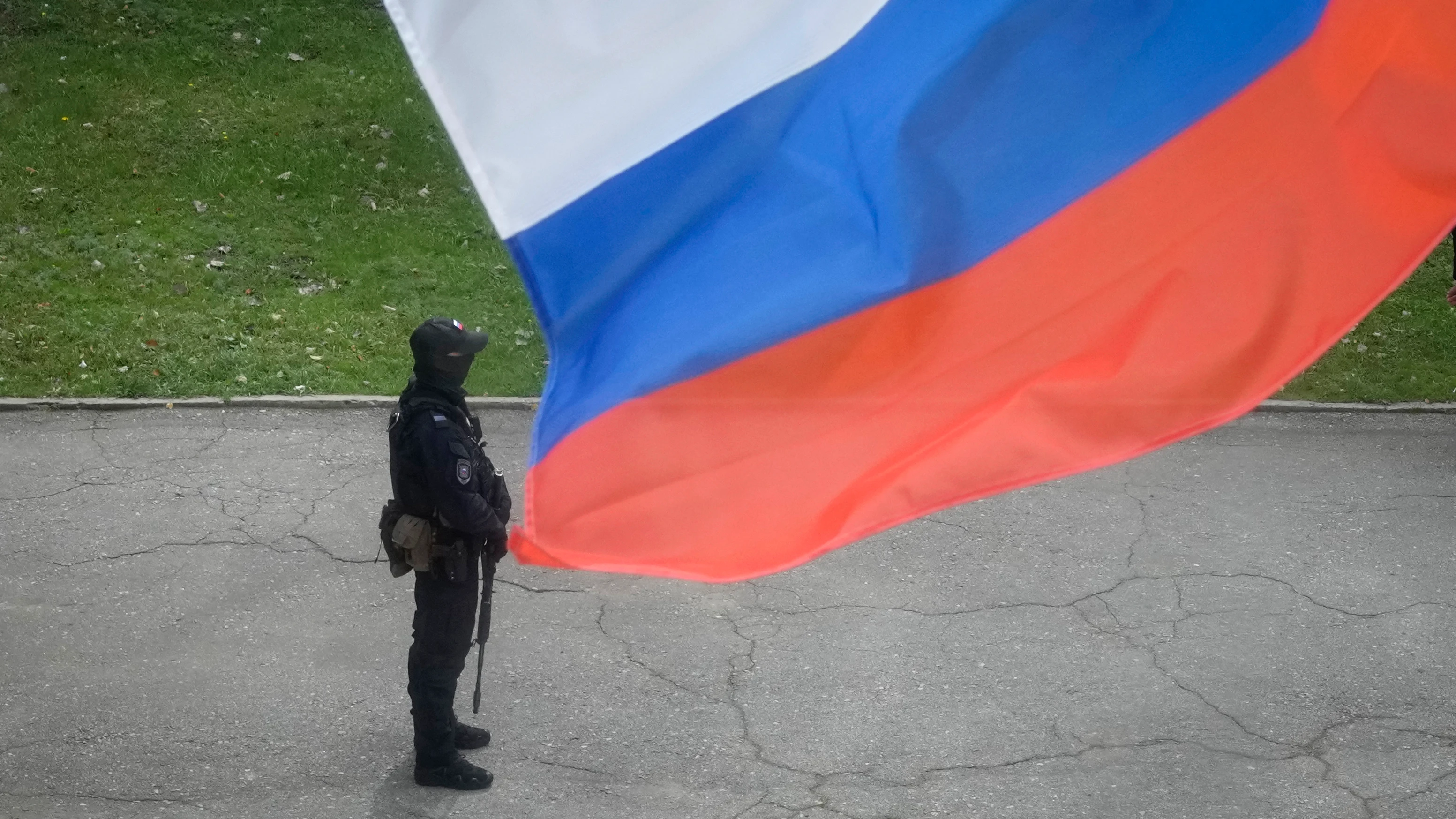 Un policía, junto a la bandera de Rusia