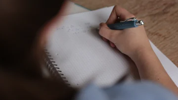 Una persona escribiendo con bolígrafo en un cuaderno