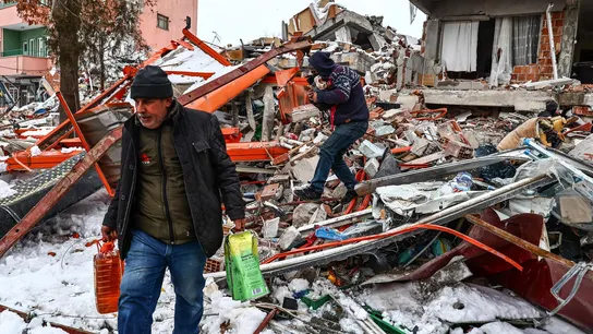 Personas llevando alimentos rescatados de un edificio derrumbado. Personas llevando alimentos rescatados de un edificio derrumbado.