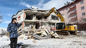 Una mujer reacciona junto a un edificio derrumbado durante las operaciones de búsqueda.