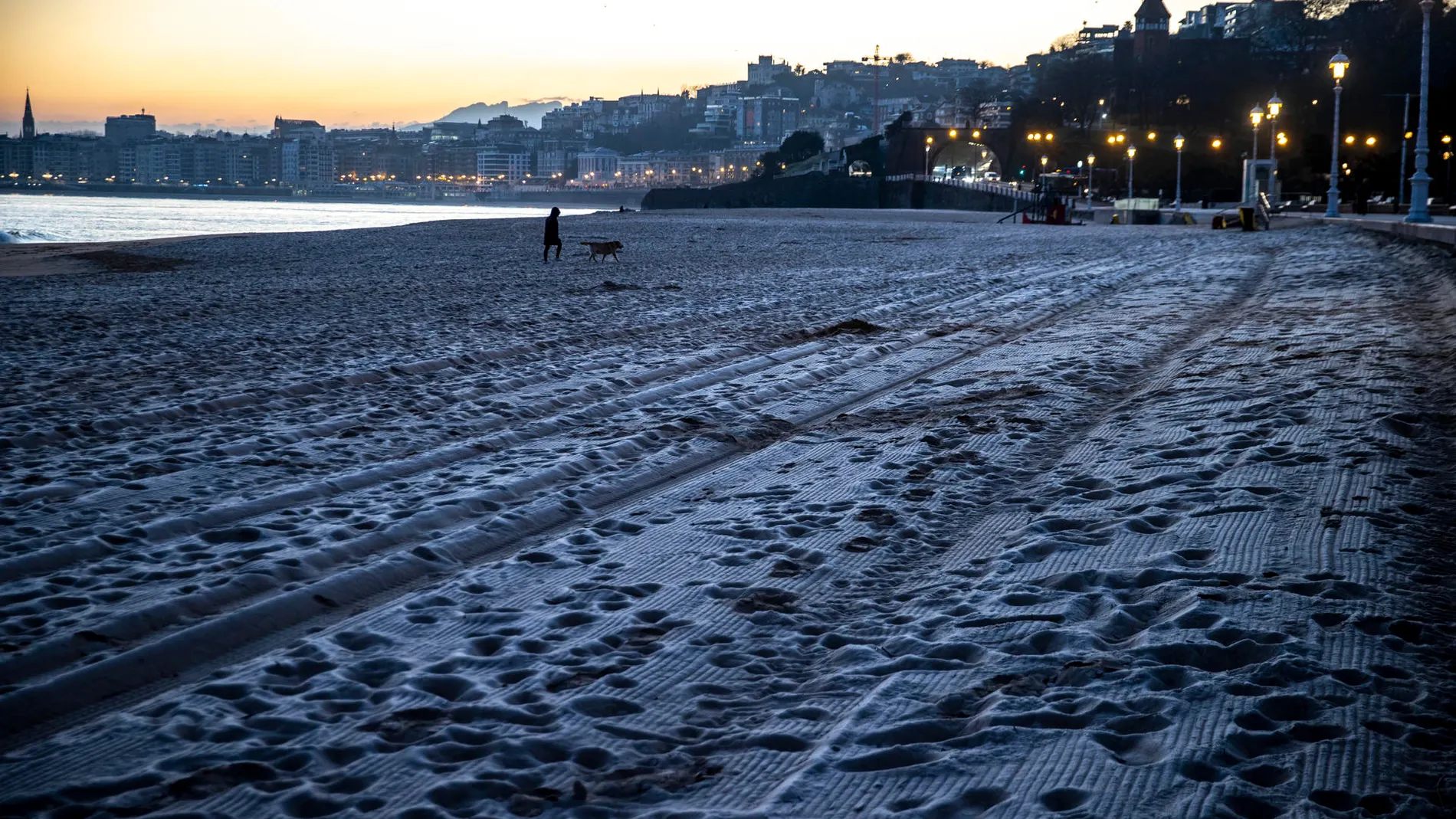 Una mujer pasea a su perro por la playa de Ondarreta de San Sebastián