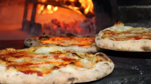 Imagen de archivo de varias pizzas en un horno de leña.