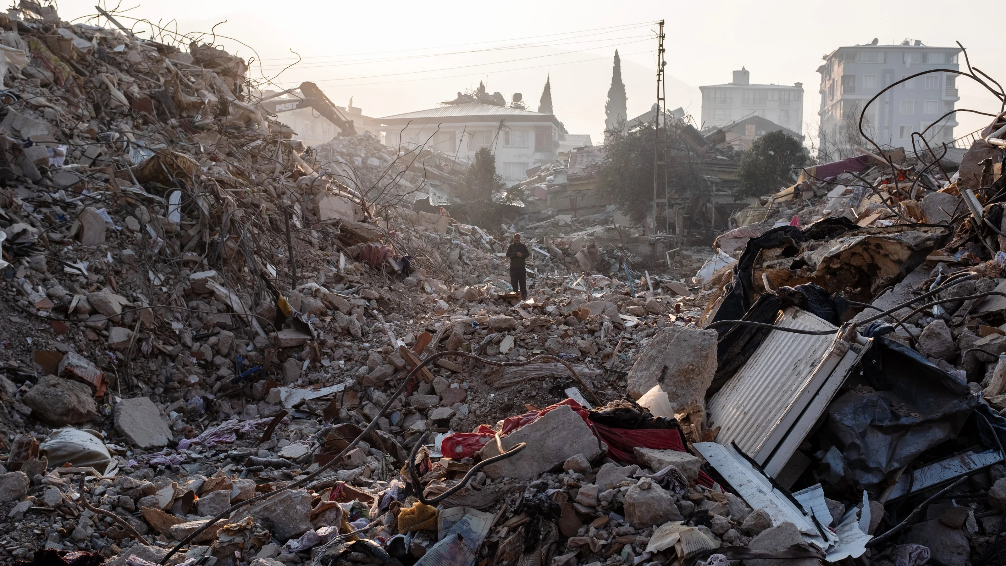 Un hombre camina entre los escombros de un edificio derrumbado mientras espera noticias de sus seres queridos el 13 de febrero de 2023 en Hatay, Turquía.