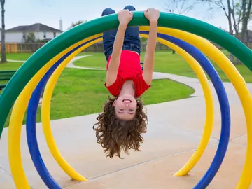 Niña boca abajo en un columpio Niña boca abajo en un columpio