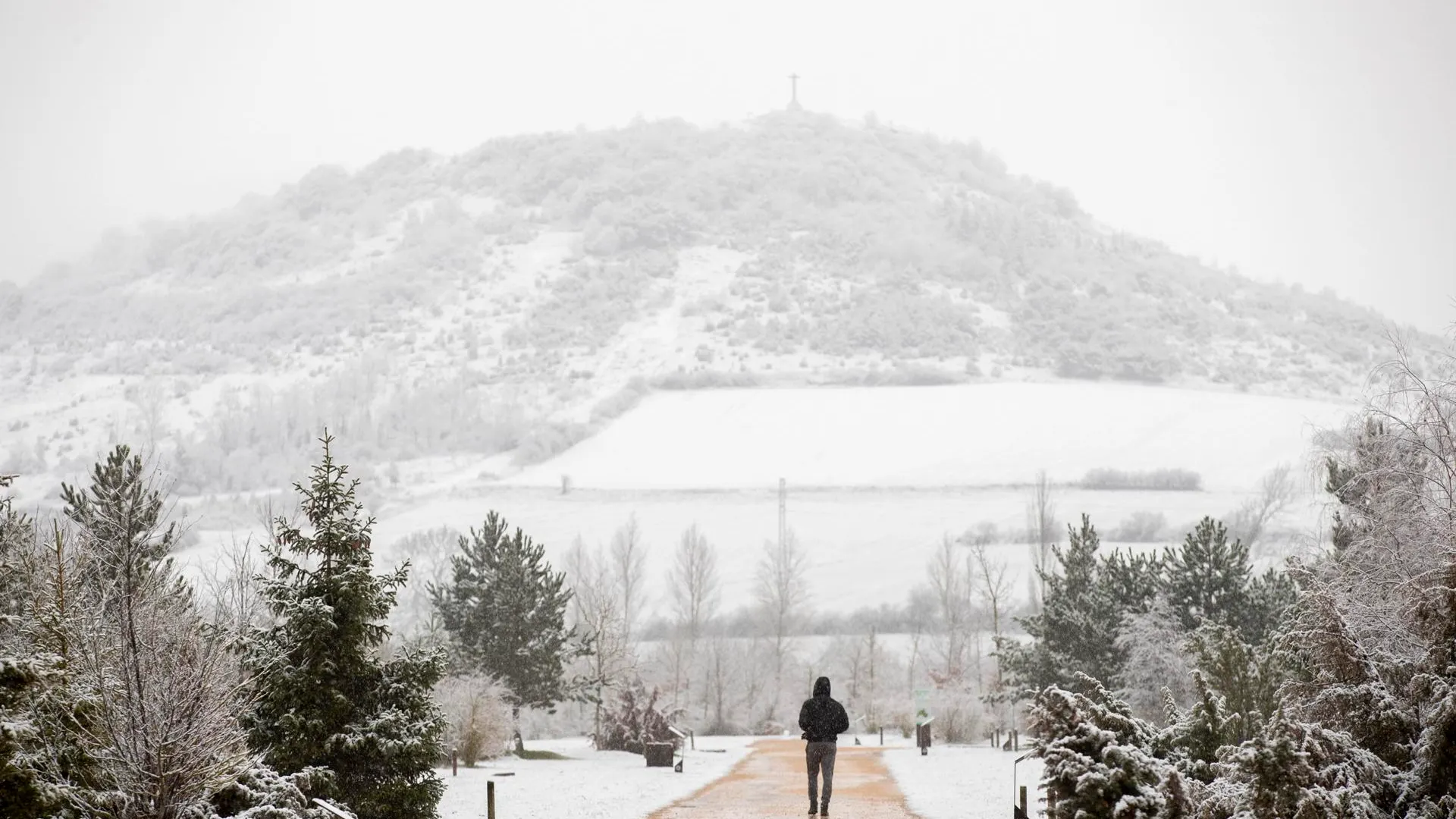 Un hombre pasea por un parque de Vitoria cubierto por la nieve en la mañana de este jueves