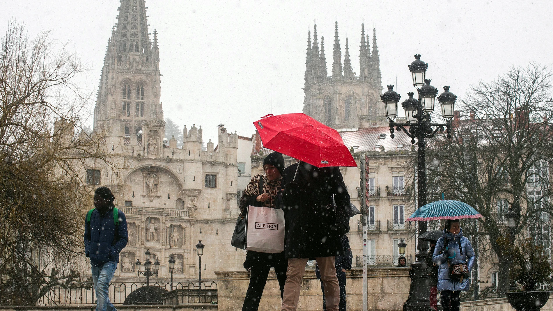 Varias personas caminan por la calle mientras nieva, a 23 de febrero de 2023, en Burgos.