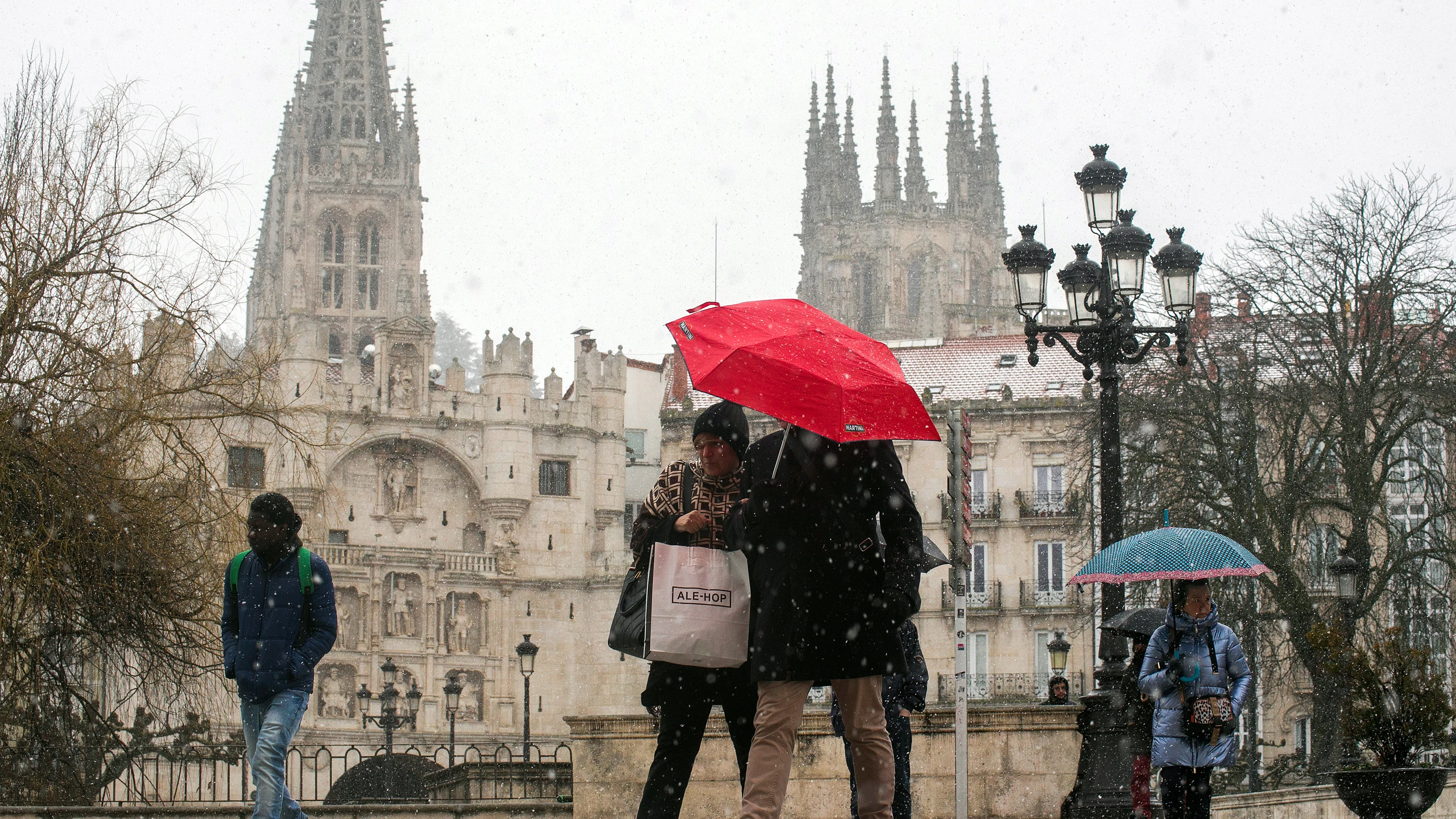 Varias personas caminan por la calle mientras nieva, a 23 de febrero de 2023, en Burgos.