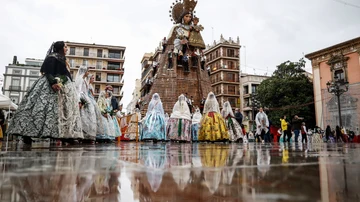Varias falleras caminan durante la ofrenda floral a la Virgen de los Desamparados.