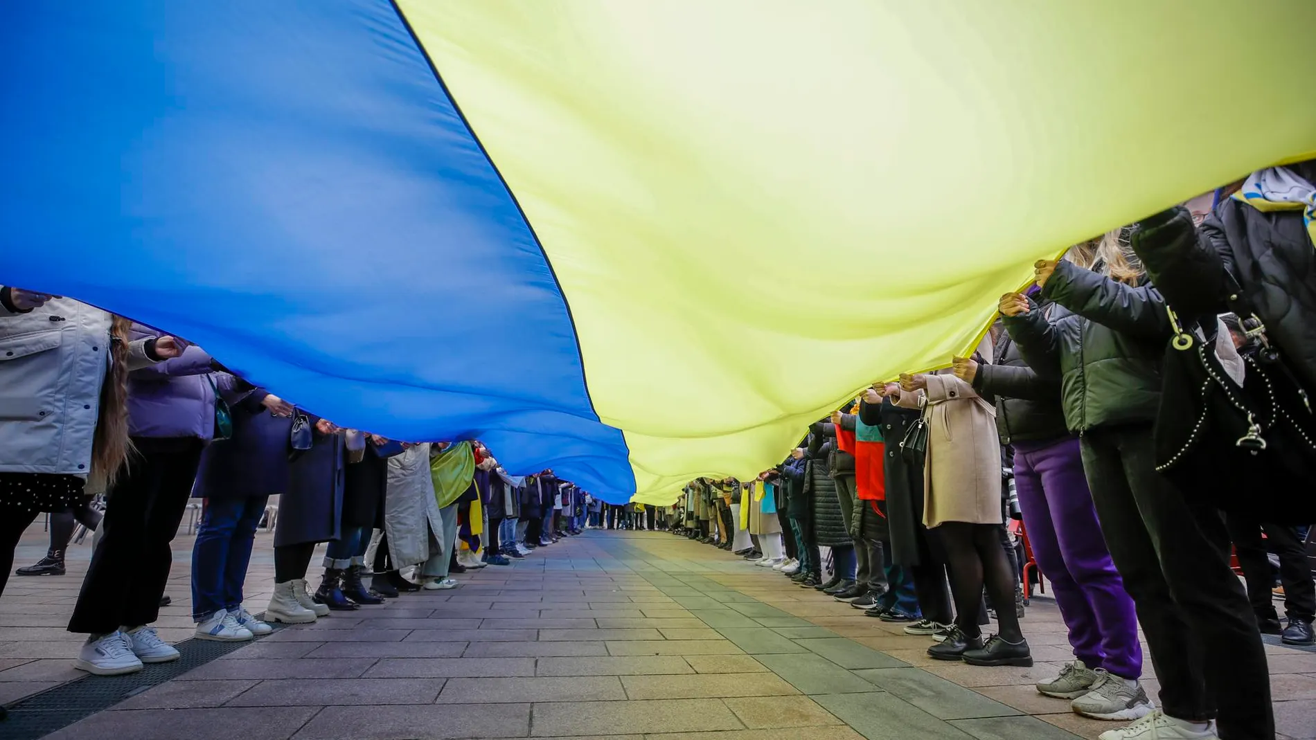 Imagen de una larga bandera extendida en Bruselas en apoyo a Ucrania en el aniversario de la invasión rusa.