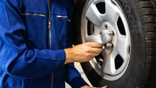 Imagen de un mecánico ajustando la rueda de un coche Imagen de un mecánico ajustando la rueda de un coche