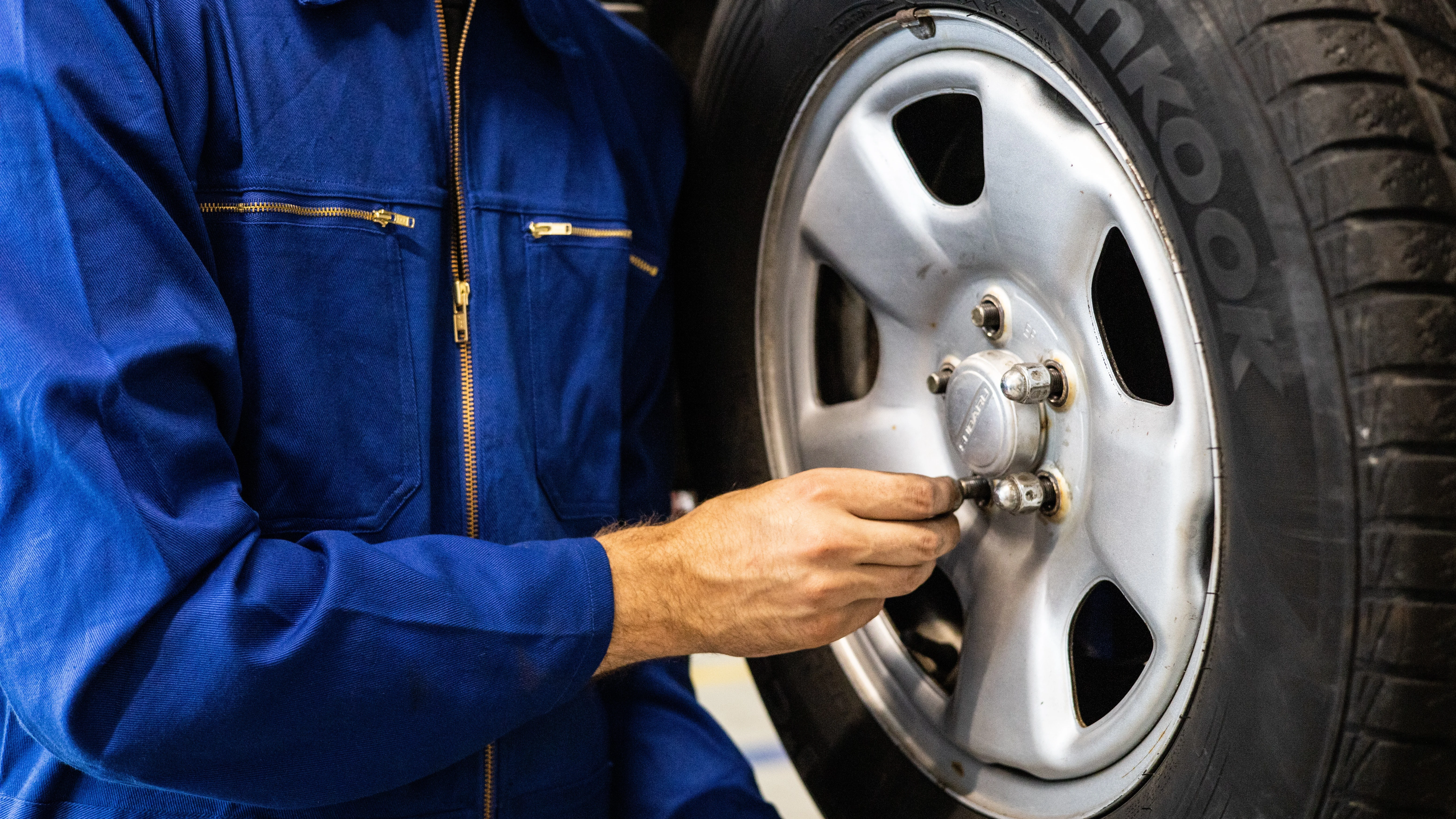 Imagen de un mecánico ajustando la rueda de un coche