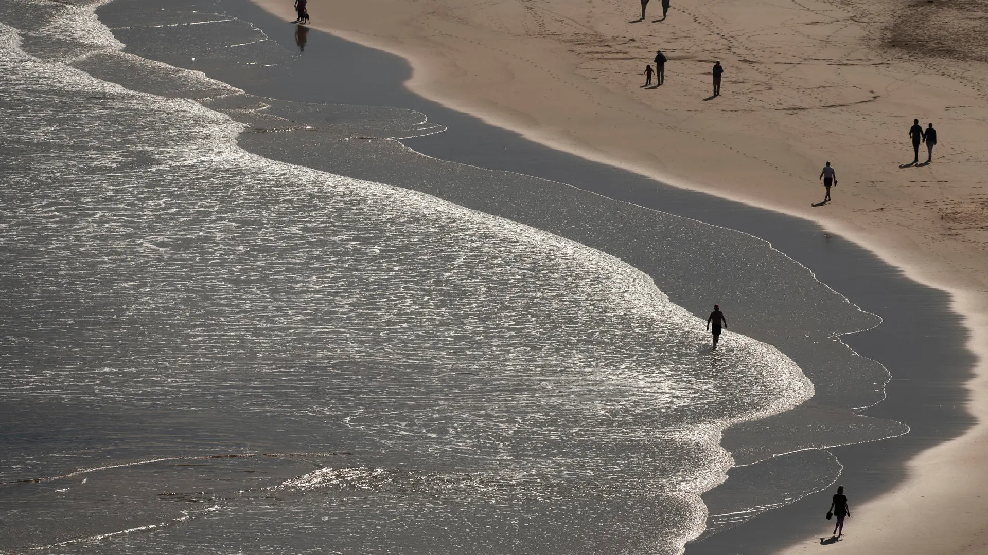 Varias personas pasean por la playa de La Concha en Suances.