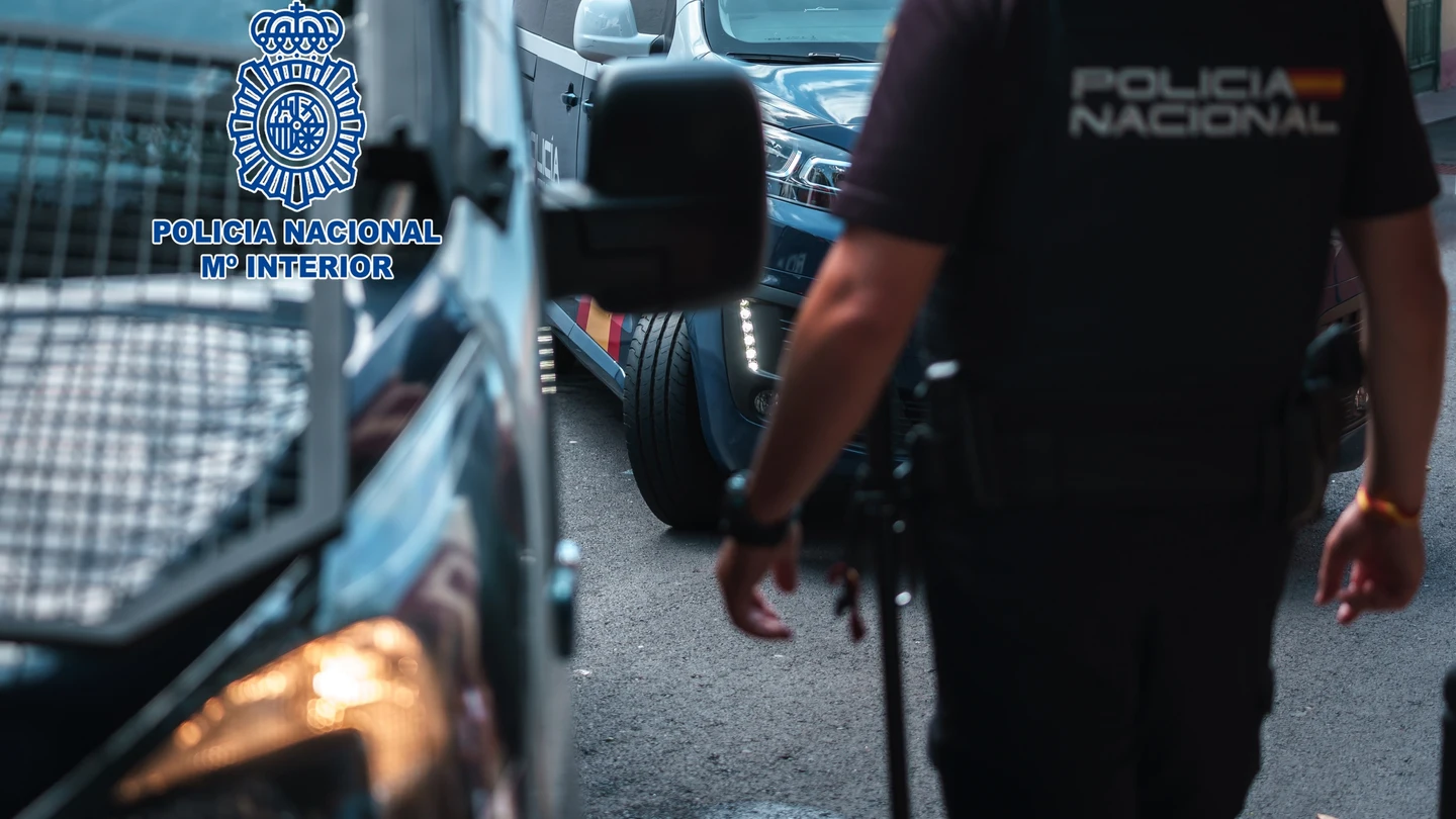 Imagen de recurso de un agente de la Policía Nacional junto a dos vehículos policiales Imagen de recurso de un agente de la Policía Nacional junto a dos vehículos policiales