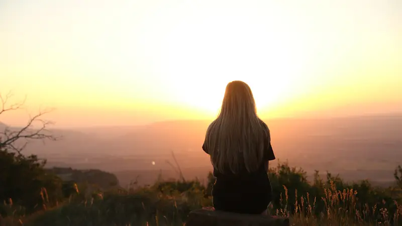 Una adolescente observa la puesta de sol