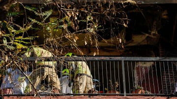 Varios bomberos trabajan en el balcón de la vivienda donde se ha declarado un incendio a primera hora de este lunes en la ciudad de Valencia.