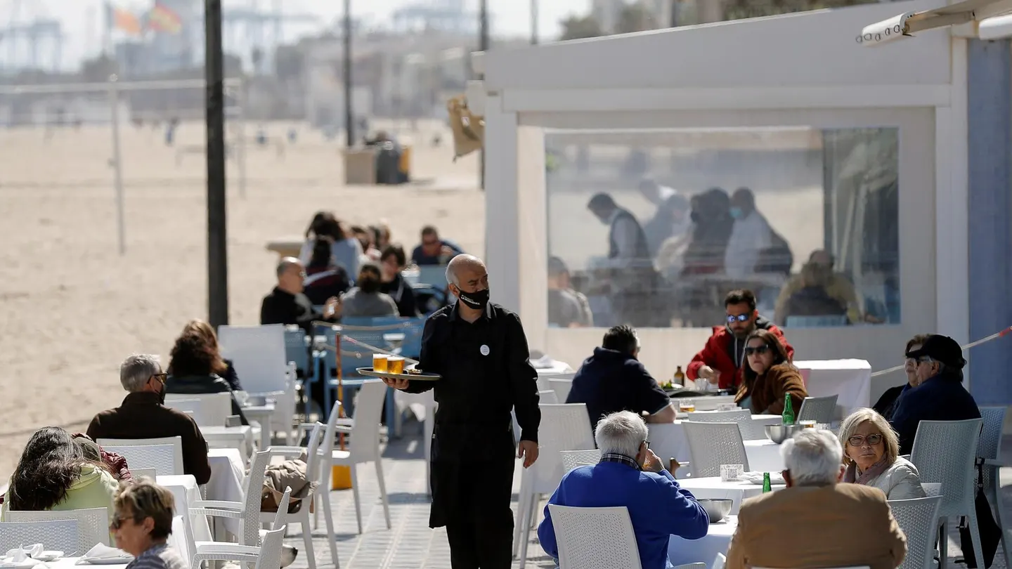 Un camarero atiende las mesas de una terraza en uno de los restaurantes de la playa de la playa de la Malvarrosa de Valencia Un camarero atiende las mesas de una terraza en uno de los restaurantes de la playa de la playa de la Malvarrosa de Valencia