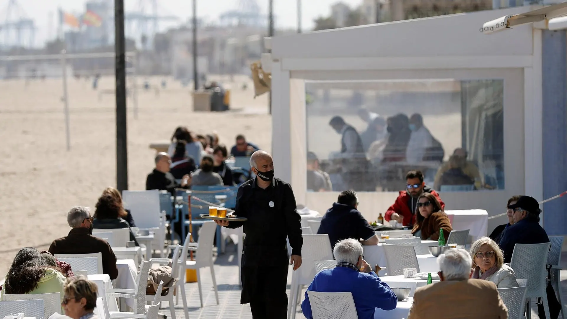 Un camarero atiende las mesas de una terraza en uno de los restaurantes de la playa de la playa de la Malvarrosa de Valencia