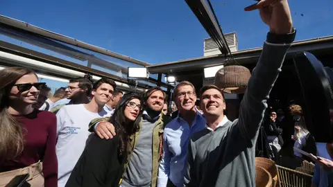 El presidente del PP, Alberto Núñez Feijóo, posa para una foto con jóvenes en un acto de vivienda en Madrid