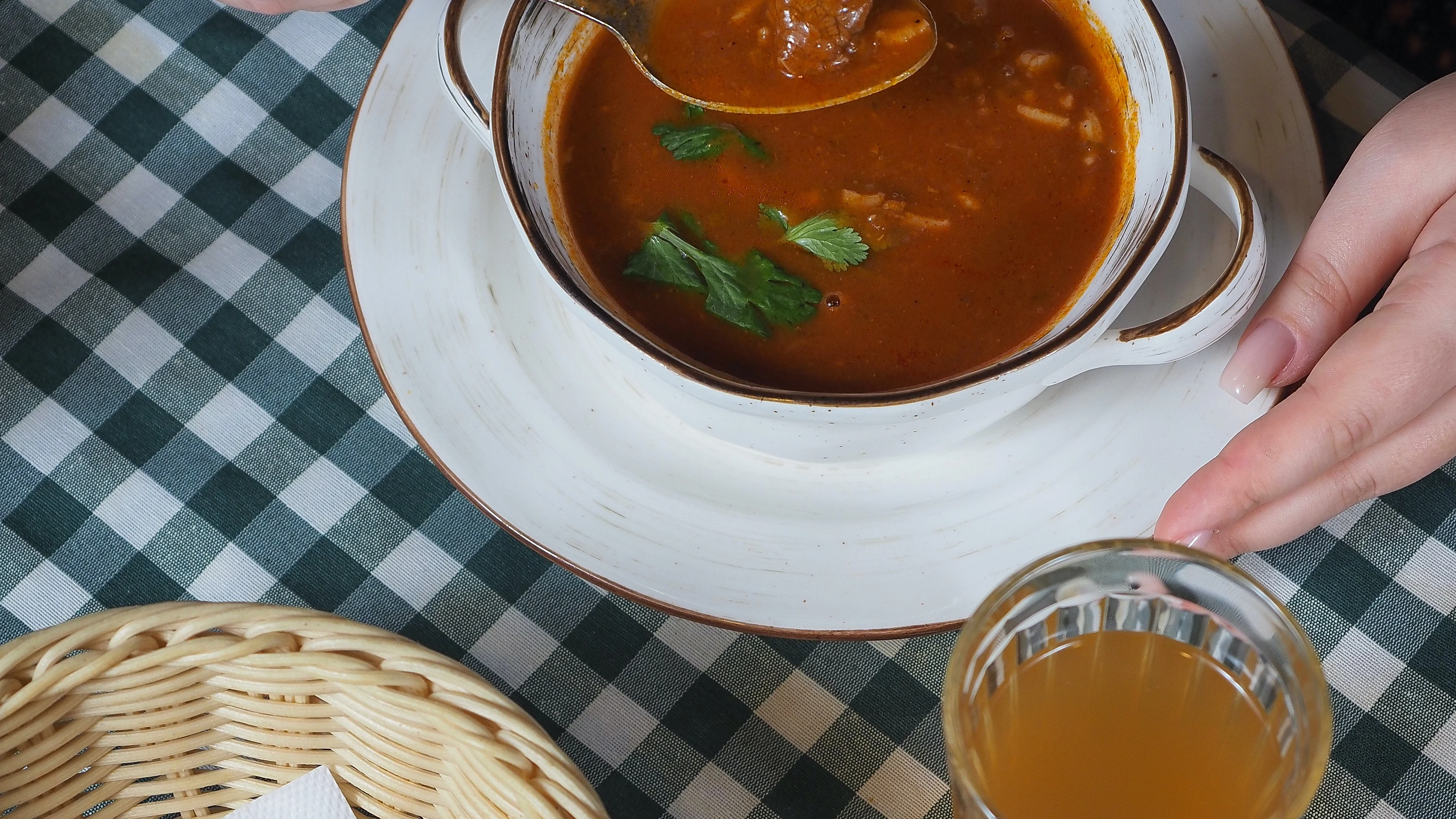 Fotografía de una sopa acompañada de una bandeja de pan y un refresco