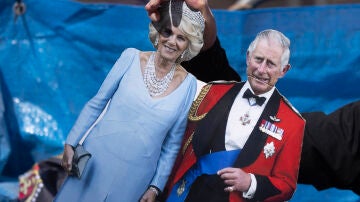 Un hombre lleva unos recortes de Camila Parker y el rey Carlos III de Inglaterra en vísperas de la coronación