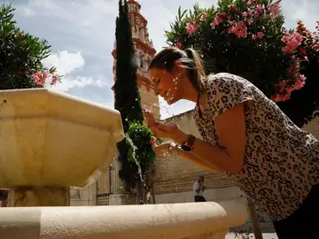 Una joven se refresca en una fuente de Écija, Sevilla, en una imagen de archivo